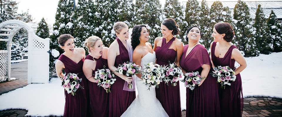 Bride and her bridesmaids holding their purple and white wedding bouquets. 