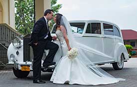 Bride and Groom kissing outside a limousine