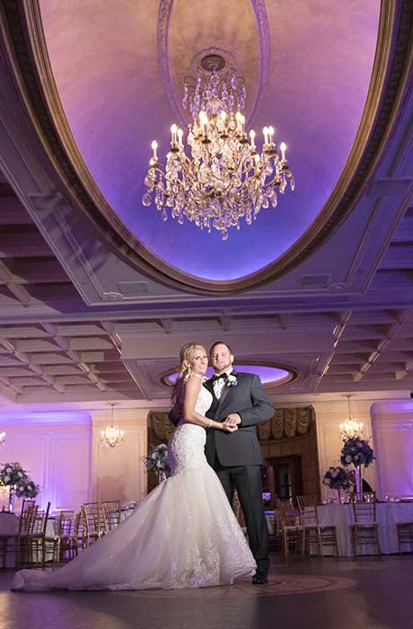 Bride and Groom standing in their reception room with purple up lighting prior to guest arriving.