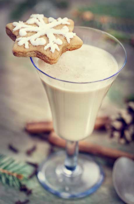 An eggnog drink with a sugar cookie placed on the rim of the glass. 