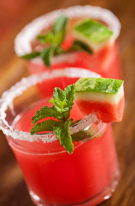 Watermelon mojito with salted and watermelon slice on rim of glass. 