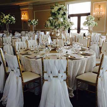 Table setup in ballroom with beautiful white chair covers. 