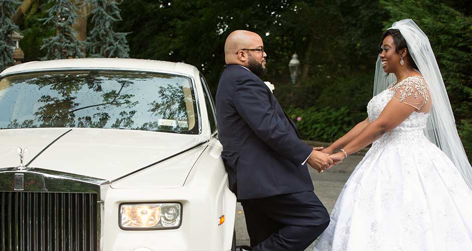 Bride and Groom looking at each other while holding hands while next to limousine. 