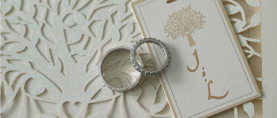 White wedding invitation with wedding bands placed on top.