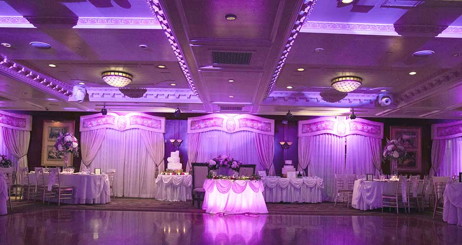 Wedding venue reception room set-up with purple up lighting. 