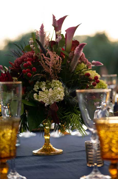 Wedding centerpiece of fall color flowers with red berries in a vintage gold vase.