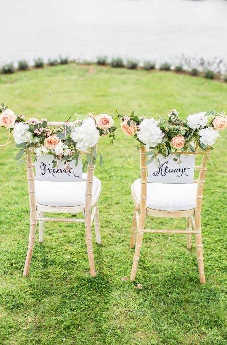 Bride and Groom wedding chairs decorated with Mr and Mrs signs with flowers.