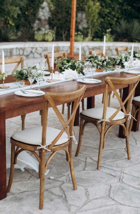 Outdoor rustic wedding table setup with chairs.