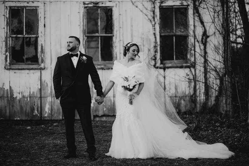 Black and white image of a bride and groom holding hands. 