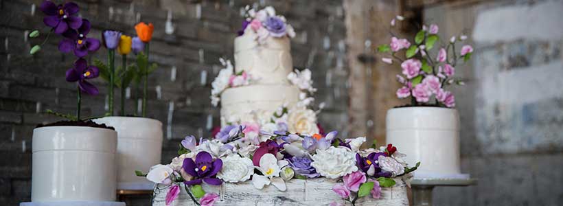 A wedding cake surrounded by colorful floral decor.