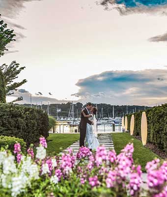 A bride and groom kissing with a harbor view backdrop. 
