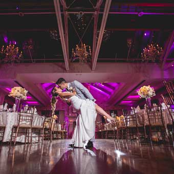 Bride and groom dancing in their reception room with purple uplighting. 