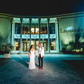 Bride and groom posing at night at the front entrance of Leonard's Palazzo.
