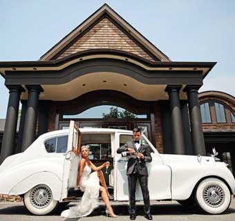 Bride and Groom standing next to a limo outside of the front entrance of Insignia. 
