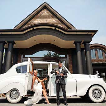 Bride and groom standing next to a limousine outside the front entrance of Insignia. 