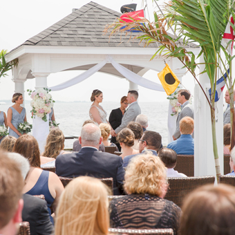 Guests watch bride and groom say their vows in an outdoor ceremony overlooking the ocean.
